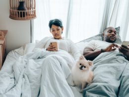 Wielorasowa para w łóżku wpatrzona w swój telefon