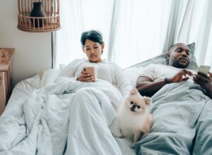 Wielorasowa para w łóżku wpatrzona w swój telefon